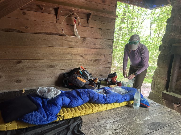 woman in backpacking shelter putting together sleeping bag