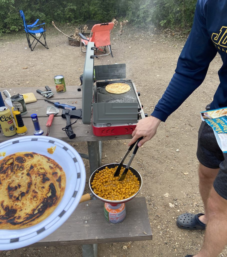 man cooking on a camp stove